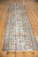 Worn pile and tattered end of Lilihan runner, with exposed foundation and faded floral vinery.