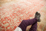 Distressed Khotan carpet featuring faded cinnabar red pomegranate motifs and dynamic abrashes.