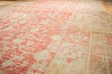 Worn antique Khotan carpet detail: faded cinnabar pomegranate motif and pale border.