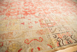 Distressed antique Khotan rug with faded cinnabar red pattern and visible knot heads.