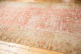 Distressed antique Khotan carpet corner with faded cinnabar red and gold stemmed pomegranate motifs.