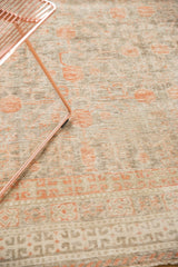 Distressed antique Khotan rug with faded pomegranate motifs, platinum, and terra cotta blush.