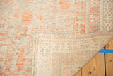 Hand-knotted Khotan rug's exposed foundation and worn pile displaying terracotta pomegranate motif.