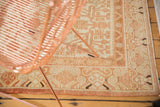 Vintage distressed Khotan rug corner showcasing geometric pomegranate motifs and intricate border.