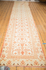 Distressed Khotan runner corner showcasing worn pomegranate motifs in ivory and faded red.