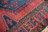 Veece rug with black cherry red field, navy geometric shapes, and gold zigzag border.