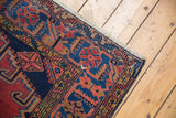 Vintage Veece hand knotted rug corner with navy, black cherry red, gold geometric pattern and fringe.