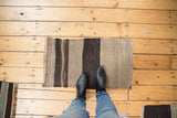 Geometric handwoven vintage Turkish Kilim mat with varied gray and charcoal stripes.