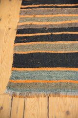 Hand-woven Turkish Kilim texture showing alternating black, earthy, and tangerine stripes.
