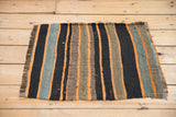 Bottom edge and fringe of a handwoven Turkish Kilim with oxidized silver, black, and orange stripes.