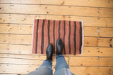 Hand woven vintage Turkish Kilim mat with varying pale wine red and brown banded striations.