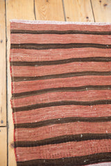 Secured side edge and flat-weave texture of the Kilim with wine red and chocolate bands.