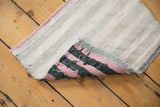 Vintage Turkish Kilim rug, folded to show its subtle banded front and pink, charcoal reverse.