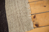 Handwoven texture and natural fringe of a vintage Turkish Kilim with beige and charcoal stripes.