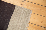 Hand woven Turkish Kilim rug edge showing contrasting beige and charcoal flatweave with fringe.