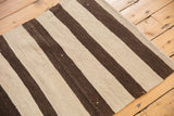 Edge of hand woven Turkish Kilim rug with chocolate brown and ivory stripes.