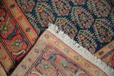 Hand-knotted vintage Malayer carpet detail: navy boteh field, orange border, and ivory fringe.