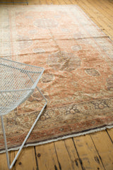 Faded pale rose field and intricate curvilinear border of a distressed Turkish Kaisery rug.