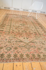 Distressed vintage Oushak rug detail with blush field, germinating tree border, and abstract motifs.