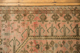 Distressed Oushak rug detail with geometric rams horn border and dusty rose field motifs.