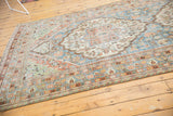 Distressed Mahal carpet close-up: faded blue, terracotta floral vinery, and worn texture.