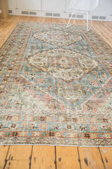 Detail of distressed vintage Mahal rug's faded blue and terracotta border with fringe.