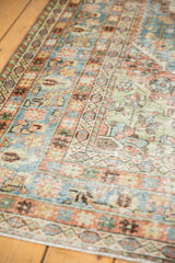 Distressed vintage Persian Mahal carpet detail: faded blue, terracotta, and green geometric patterns.