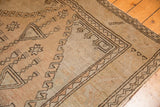 Distressed vintage Oushak rug corner showing even low pile and faded geometric black motifs.