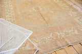 Distressed Oushak border with stylized cloud bands and floral motifs in dusty gold, pale blush.