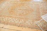 Distressed Oushak rug corner, showing cloud band border and faded florals in blush and gold.