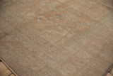 Distressed vintage Oushak carpet showcasing low pile texture and muted apricot-sand hues.