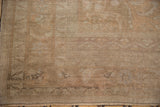Distressed Oushak rug's low pile texture with muted sand, ivory, and faded apricot.