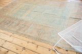 Distressed vintage Oushak rug corner with faded scrolling vinery and wide border.