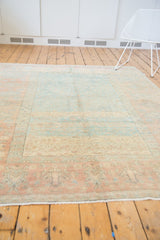 Distressed Oushak rug with wide terracotta border, oversized vinery, and faded blue-ivory field.