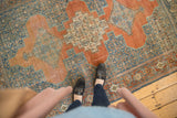 Distressed vintage Senneh rug with terracotta triple medallion, blue Herati field, and even wear.