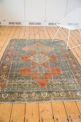 Distressed vintage Senneh rug border featuring intricate terracotta, blue, ivory patterns and worn pile.