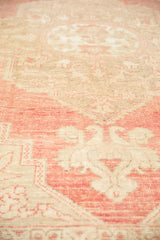 Distressed Oushak rug's textured pile, blush pink, antique ivory, and faint foundation.