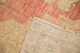 Distressed vintage Oushak carpet pile, muted red and beige, with original selvage and woven back.