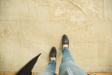 Ivory distressed Oushak rug texture with faint geometric medallions and soft abrash.