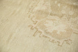 Low pile texture on a distressed Oushak rug with faded ivory geometric patterns.