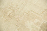Low pile texture and excellent abrash on distressed ivory Oushak rug, showing faint geometric patterns.