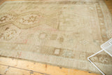 Distressed Oushak rug corner, showing muted beige, coffee brown, and pale blush geometric patterns.