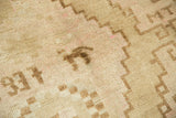 Vintage distressed Oushak rug's unique weaver's mark in blush and pale beige pile.