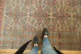 Distressed vintage Kayseri rug with geometric floral pattern and muted tones, visible underfoot.