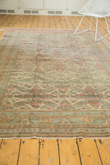 Angled view of distressed Kayseri carpet, with geometric floral motif in muted ivory, terra cotta, and green.