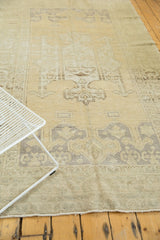 Distressed vintage Oushak rug showing geometric spandrel pattern in soft beige and faded blue.