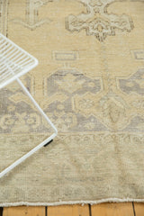 Distressed Oushak rug with faded beige and blue geometric patterns, featuring even wear.