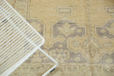 Distressed vintage Oushak carpet pile with faded beige and dusty blue geometric patterns.