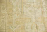 Distressed Oushak rug with even pile wear, faint foundation showing, and soft beige tones.