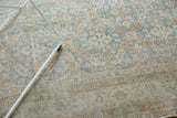 Distressed Oushak carpet texture with faded floral lattice in slate blue and sand.